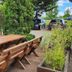 Outdoor wooden picnic tables at Zur Fichtenbreite in Klieken beside parked cars and greenery