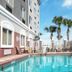 Country Inn & Suites by Radisson, St. Petersburg pool with palm trees and patio seating in Pinellas Park