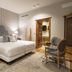 Hotel Cetina Palacio de los Salcedo room in Baeza with king bed, patterned wall, seating area and open wardrobe
