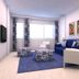 Tahití Playa Suites in Santa Susanna, bright suite with blue sofa, chairs, ottomans and large window