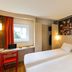 ibis Aulnay Paris Nord Expo room in Aulnay-sous-Bois with two twin beds, desk, window and city wall art