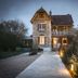 Domaine De La Corniche in Rolleboise, stone hotel exterior at dusk with lit windows and a gravel drive