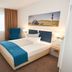 Hotel Nordraum Bremen guest room with double bed, blue chair, desk, and lighthouse wall art