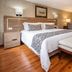 Hotel Porton De La Cabrera room in Bogotá with king bed, bench, desk and warm wood flooring