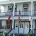 Lost Bayou Guesthouse in Galveston, historic white two-story facade with balconies and flags
