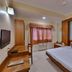 Hotel G Shy, Bhopal guest room with double bed, desk, window AC and wall-mounted TV