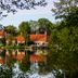 Åsby Hotell in Hallstahammar with red-roofed buildings reflected in a calm lakeside view
