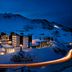 Hotel Zurserhof in Zürs lit at night, nestled in snowy mountains with glowing windows and road light trails