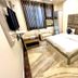 Amrit Villa New Delhi guest room with king bed, sofa, TV, and marble-style floor