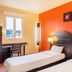 B&B HOTEL Agen Castelculier twin room with orange accent wall and window view in Castelculier