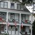 Lost Bayou Guesthouse in Galveston, white historic house with festive balcony and American flag