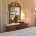 Lost Bayou Guesthouse Galveston bedroom with floral bedspread, vanity mirror and floor lamp