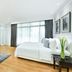 Centre Point Hotel Chidlom Bangkok bedroom with king bed, TV cabinet, sofa, and large window curtains