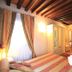 Art Palace - Residenza Giardini Venice guest room with striped bed, wooden beams, curtains and TV