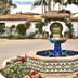 Casa Tropicana San Clemente courtyard fountain with tiled plaza, arched entry, palms, and benches