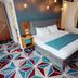 The Cube Hotel Birmingham room with geometric carpet, king bed, desk and mirrors in Birmingham