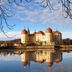 City Hotel Dresden Radebeul in Radebeul reflected in a calm lake beside a castle-like building