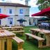 The Railway Inn in Brixham with outdoor picnic tables and umbrellas on a grassy patio