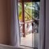 Pousada Mar de Araçatiba balcony door with tropical palm and partial ocean view in Vila do Abraao