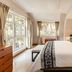 Hotel Porton De La Cabrera in Bogotá guest room with large bed, bench, dresser, and bright windows