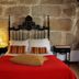 Alvares Cabral Guest House in Porto, stone-walled guest room with ornate iron bed and red bedspread