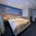 Sea You Hotel Noordwijk room with double bed, ocean mural, and mirror in Noordwijk
