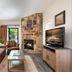 Gatlinburg Town Square living room with stone fireplace, TV, sofa and wooded balcony view in Gatlinburg