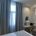 Palladion Boutique Hotel in Árgos guest room with sofa, wall TV, desk and tall window with curtains