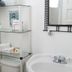Lost Bayou Guesthouse Galveston bathroom with glass shelves, sink, mirror, and folded towels