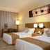 Gloria Grand Hotel Nanchang guest room with two beds, desk, lamps and floor-to-ceiling curtains in Nanchang