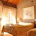 Colina del Valle in Mina Clavero: rustic twin room with wood ceiling, brick walls, and sunlit curtains