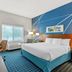 Comfort Inn & Suites Berea guest room with king bed, TV, window seat, desk and blue patterned carpet