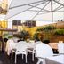 Boutique Hotel Yöpuu courtyard dining terrace in Jyväskylä with white chairs, tables and umbrellas