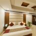 Hotel Impress By Rmr Hotels in New Delhi guest room with king bed, sofa, and modern ceiling design