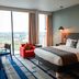 The Cube Hotel Birmingham room with city view, bed, desk and red chair in Birmingham