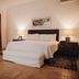 Hotel Boutique Casareyna Puebla City guest room with king bed, bedside lamps, wardrobe and terracotta tile floor