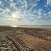 Hotel De La Plage in Valras-Plage with a sandy beach, tire tracks, and calm sea under a cloudy sky