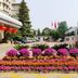 Guoyi Hotel Beijing exterior with colorful flower beds, entrance driveway, parked bus and flags