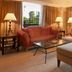 Sheraton Pilar Hotel & Convention Center suite with sofa, armchair, ottoman and large windows overlooking palms in Pilar