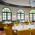 Leonardo Hotel & Residenz München dining room with round tables, mustard chairs and arched windows in Munich