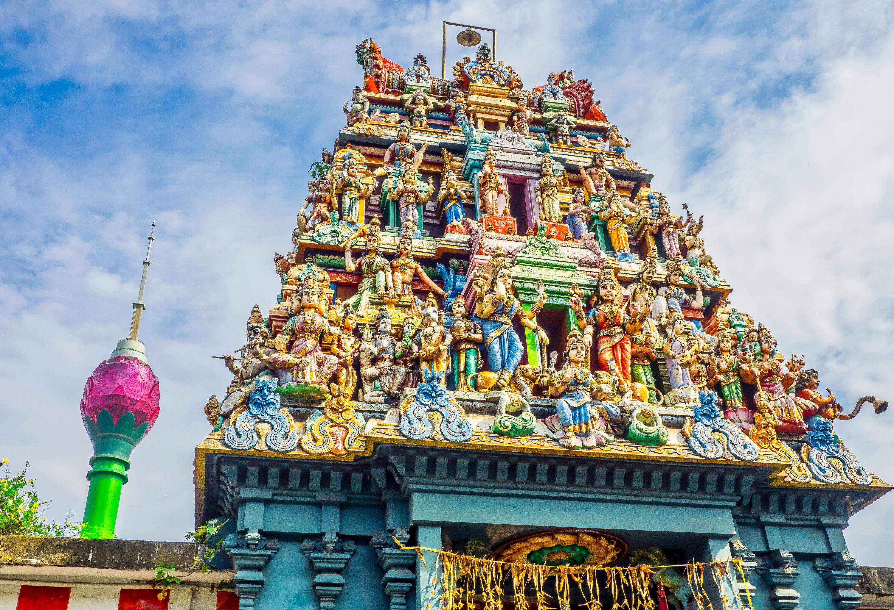 A Hindu temple with intricately designed tiered roof featuring colourful sculptures of human figures.