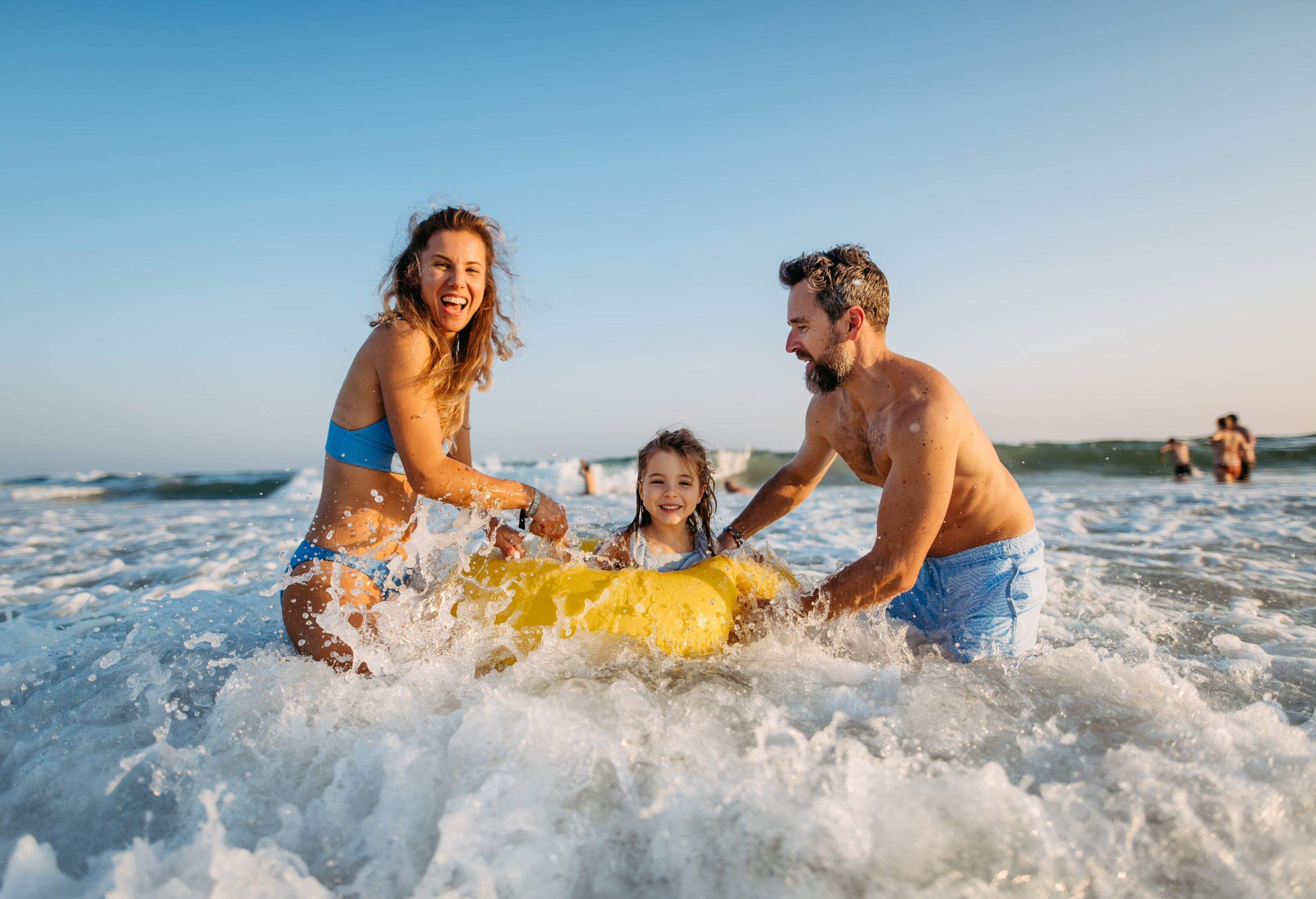 Young family with little children enjoying time at sea, having fun together.