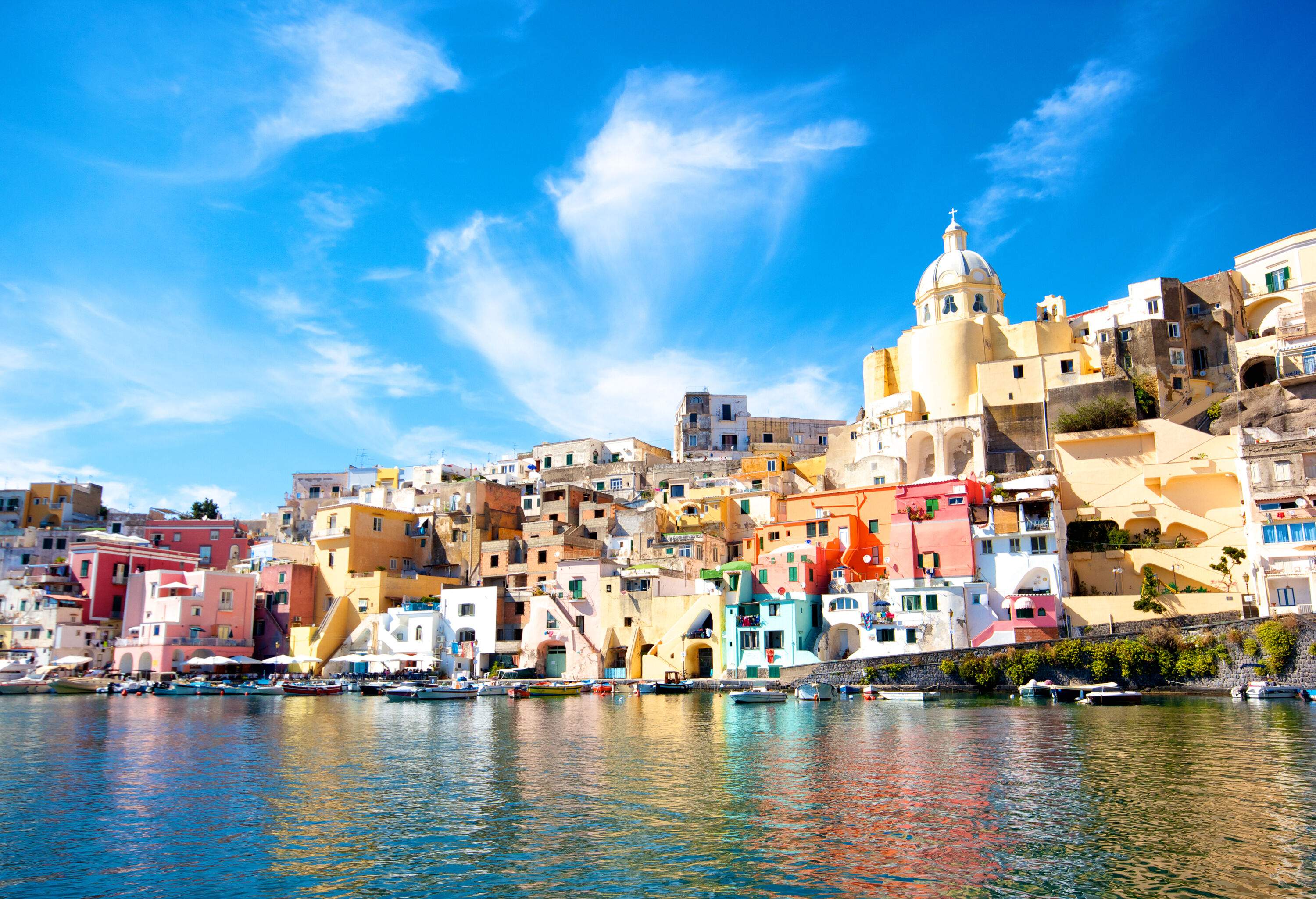 A seashore hill with brightly painted buildings in the Mediterranean style.