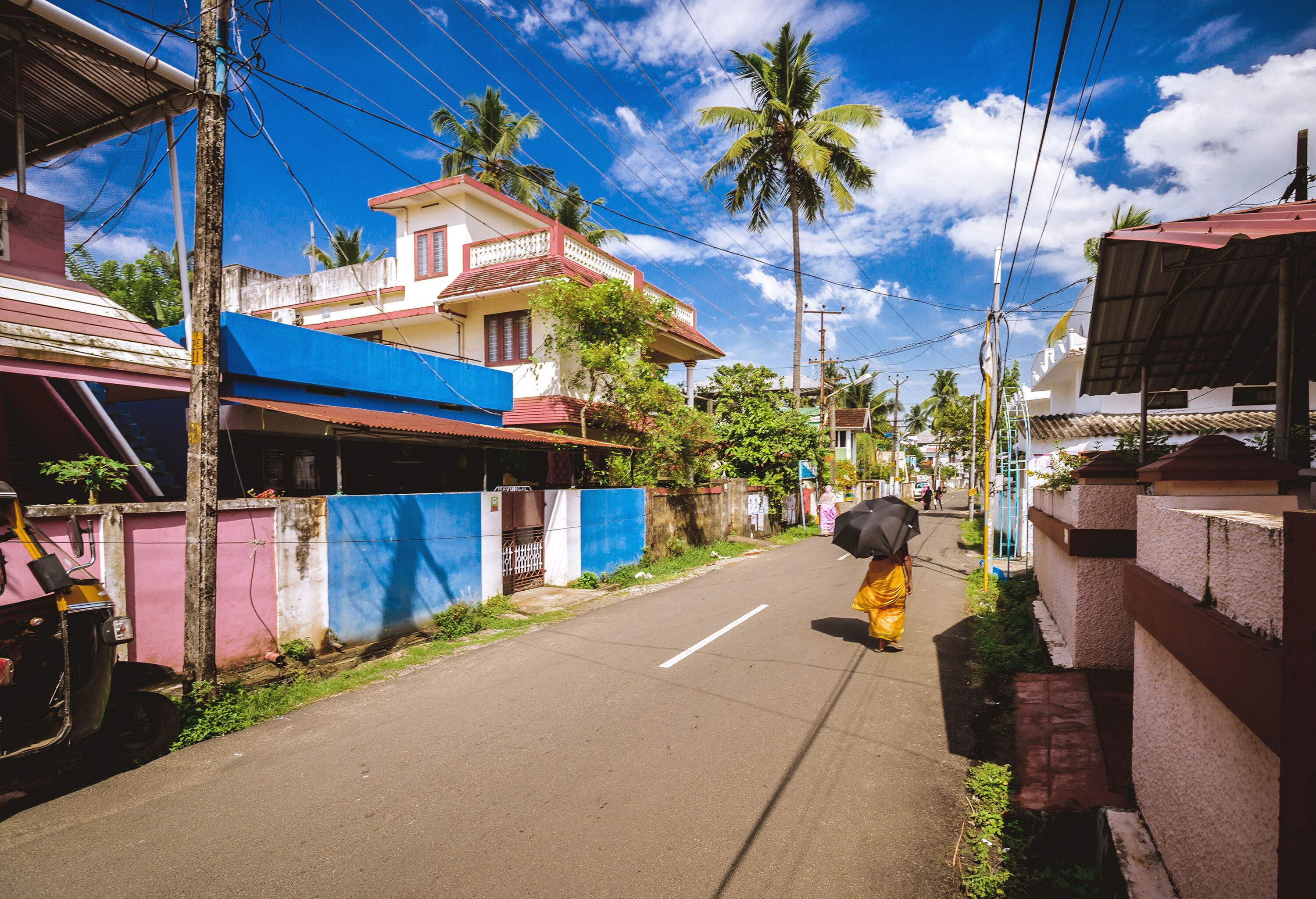 An individual walks on a street lined with traditional houses against the clear blue sky.