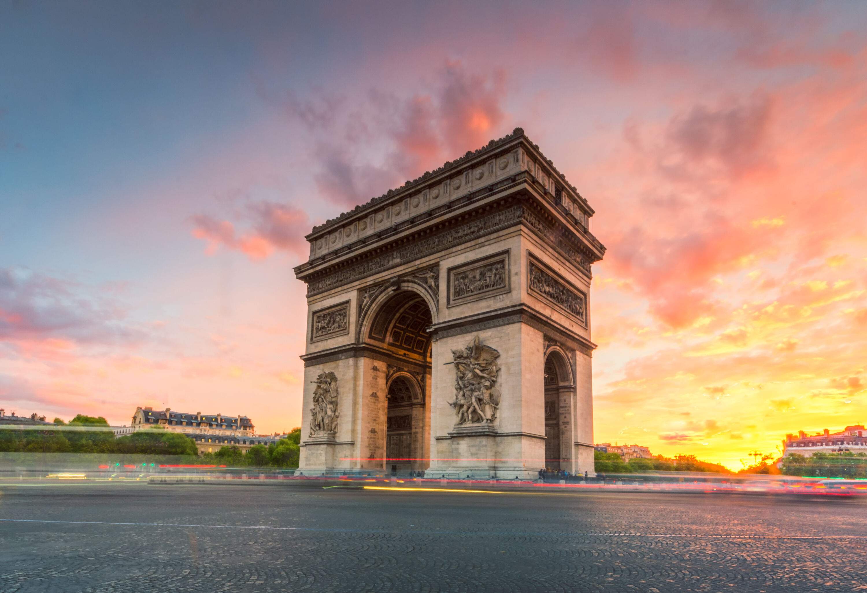 A famous monument called the Arc de Triomphe in Paris, France against the twilight sky.