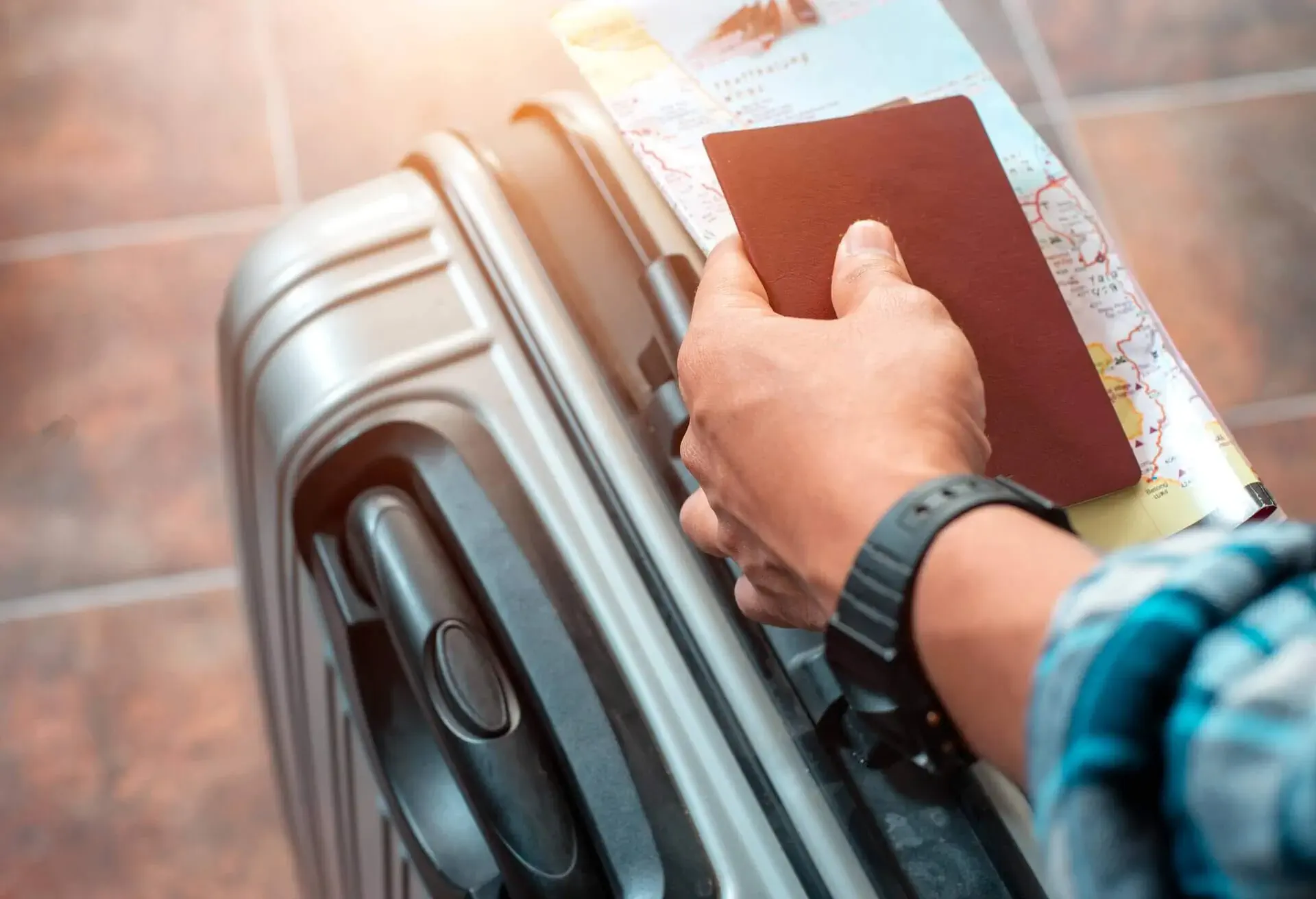 Someone holding their passport in their hand while pushing their suitcase