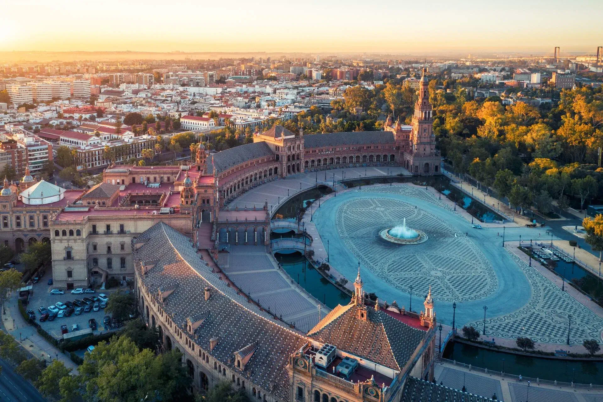 A huge half-circle plaza surrounded by a building complex accessible through the bridges and with a fountain in the centre.