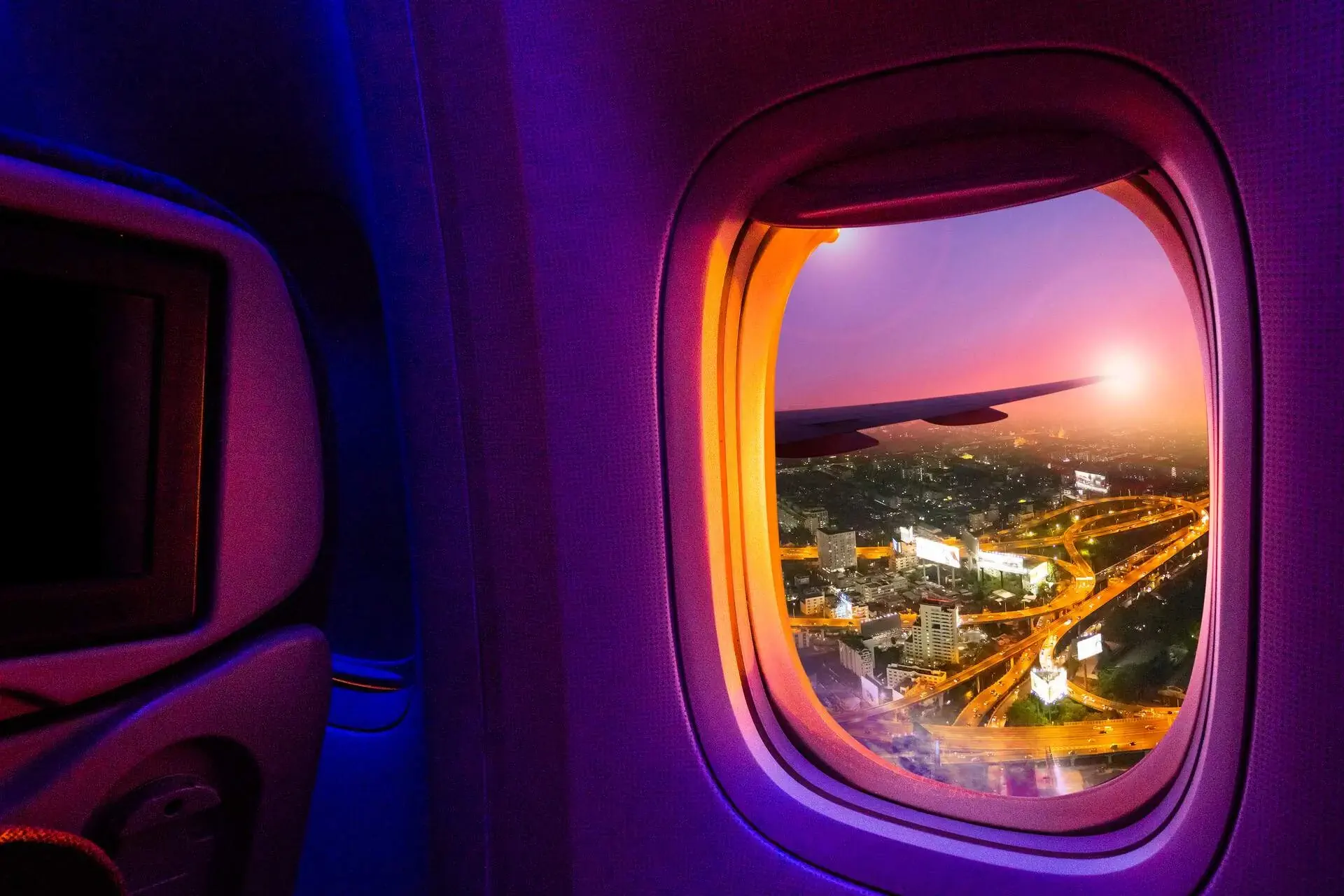 Illuminated bustling streets across the city viewed through the airplane's window.