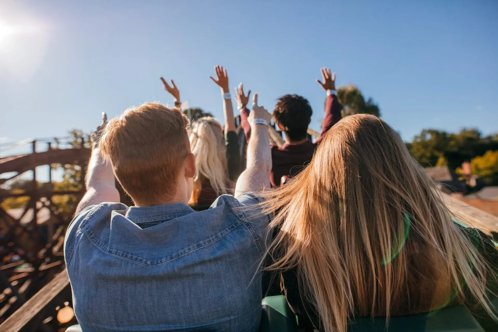 People on a roller coaster ride raise their hands.