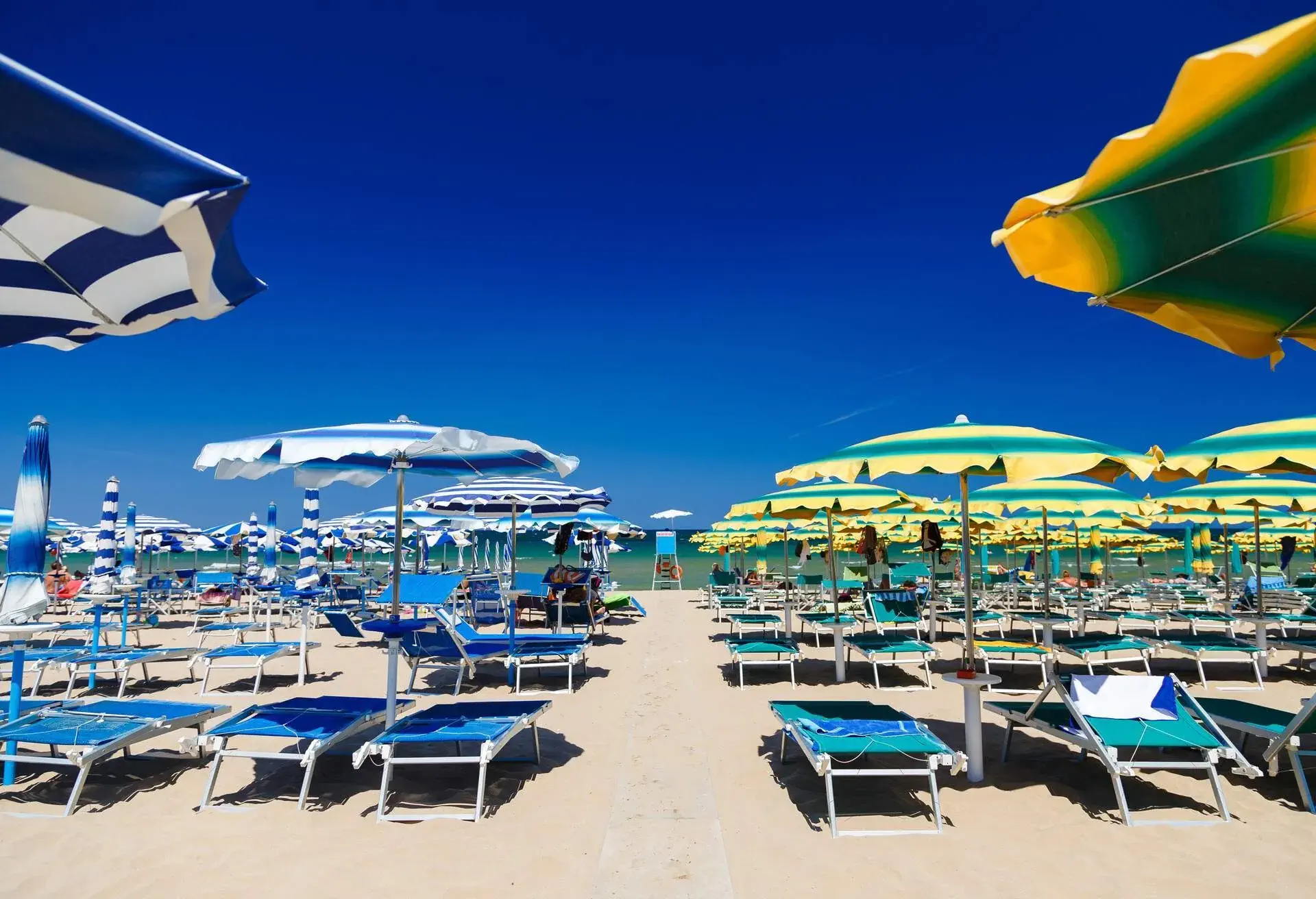 A vibrant and lively beach adorned with colourful sun beds and parasols.